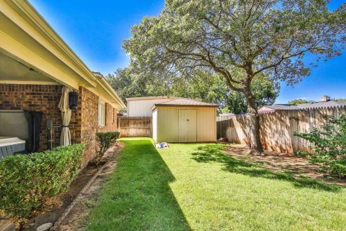 a yard of a house with a tree and a fence at Hot Tub, Privacy, sleeps 11 & TONS of Space! in Lubbock