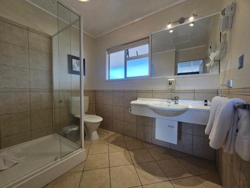 La salle de bains est pourvue d'un lavabo et d'une douche. dans l'établissement Tui Oaks Motel, à Taupo