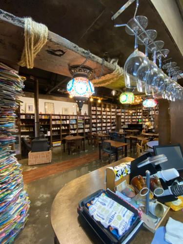 Ganderak Guesthouse في جيجو: مكتبة بها طاولة ورفوف كثيرة من الكتب