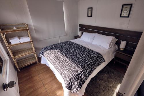 a bedroom with a bed with a black and white blanket at Lodge Sol De Cáhuil in Pichilemu