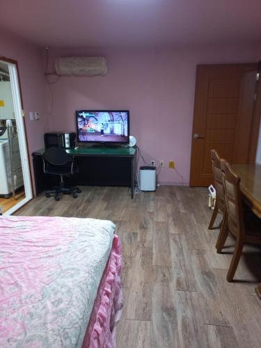 um quarto com uma cama, uma mesa e uma televisão em Esther Queen House em Gwangju