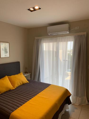 Un dormitorio con una cama amarilla y una ventana en Amaru - Amplio departamento céntrico con cochera en Corrientes