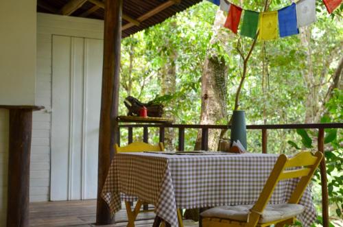 a table and chairs on a porch with a table and a umbrella at Quinta do Cajú in Ilha de Boipeba