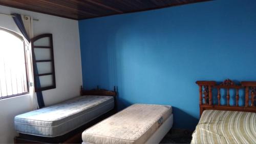 Chácara da Tia Elaine في ريبيراو بيريس: سريرين في غرفة ذات جدار أزرق