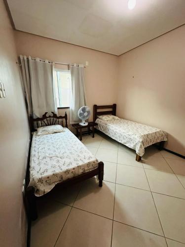 a bedroom with two beds and a window at Portal do Mar-Casa 01 in Luis Correia