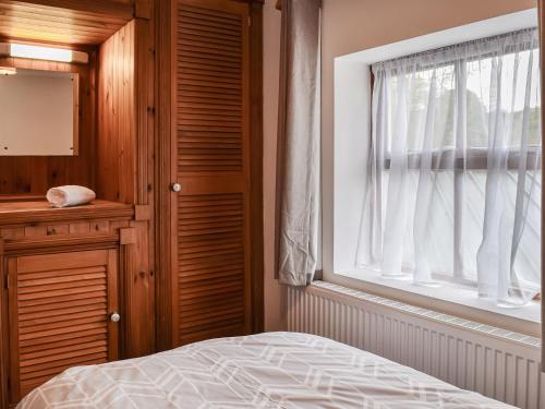 a bedroom with a bed and a window at Voelas Cottage Annexe in Llong