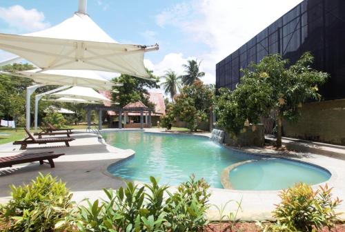 a pool with an umbrella next to a building at Avasta Resort and Spa in Anuradhapura