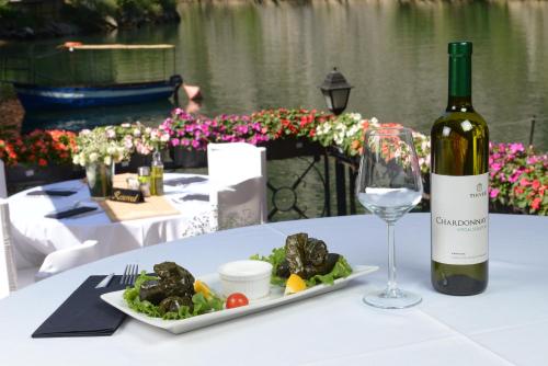a bottle of wine and a plate of food and a wine glass at Canyon Matka Hotel in Matka