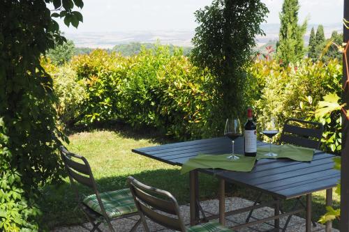 a picnic table with a bottle of wine and two chairs at Villetta Pia in Contignano