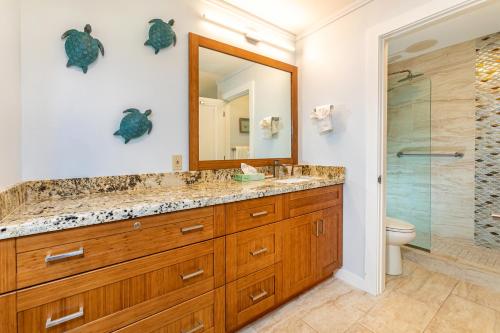 a bathroom with a sink and a toilet and a mirror at Kauhale Makai 122 in Kihei
