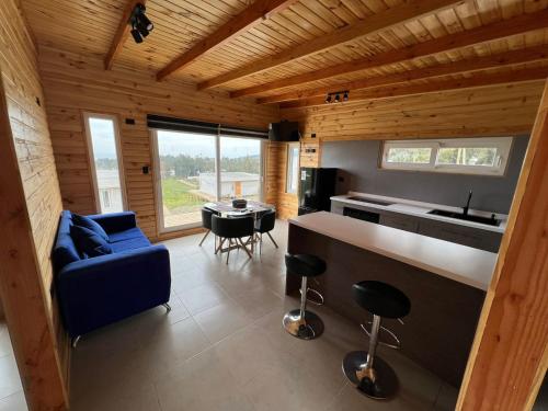 ein Wohnzimmer mit einem blauen Sofa und einer Küche in der Unterkunft Cabañas Santa Elena in Pelluhue