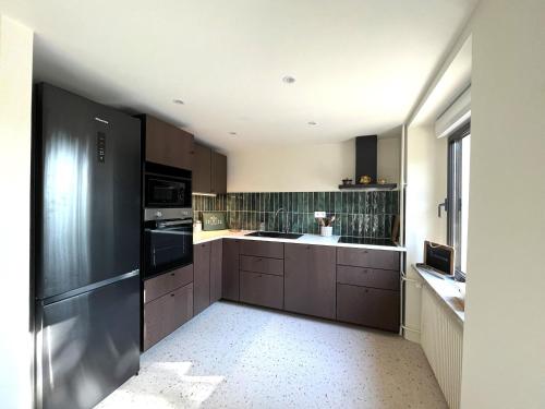 une cuisine avec des armoires marron et un réfrigérateur noir dans l'établissement Maison de charme rénovée avec terrasse, centre de Thann, proche vignobles et randonnées - FR-1-744-35, à Thann