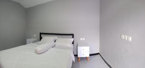 ein weißes Schlafzimmer mit einem Bett mit weißer Bettwäsche und Kissen in der Unterkunft Mount Rinjani Guest House in Sajang