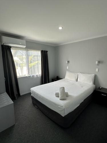 a bedroom with a white bed with a towel on it at Eastland Pacific Motor Lodge in Opotiki