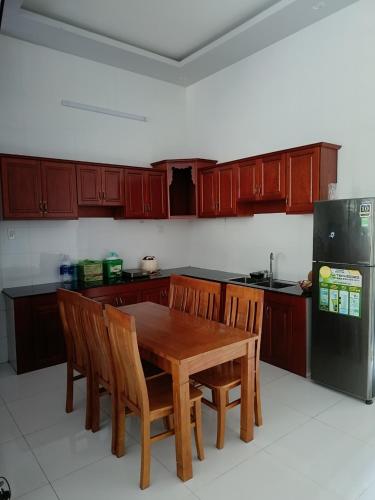 芹苴的住宿－Kim Ngân 2's，厨房配有木桌、椅子和冰箱。