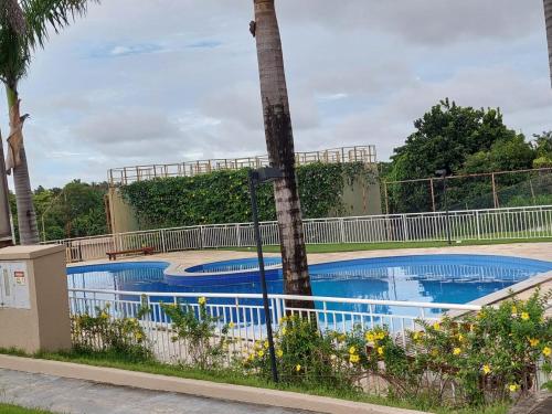 a swimming pool with a palm tree next to a fence at A FELICIDADE MORA AQUI in São Luís