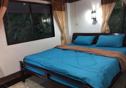 ein Schlafzimmer mit einem Bett mit blauen Laken und einem Fenster in der Unterkunft Ban Rabiengfah Resort in Ban Seng Choi