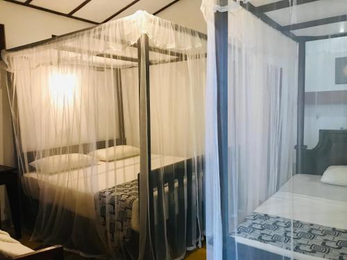 a bedroom with a canopy bed with white curtains at Ganesh Garden Beach Cabanas in Tangalle