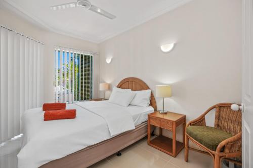 a bedroom with a bed and a chair and a window at Cairns City Family Apartment - Wifi -Netflix - Pool in Cairns North