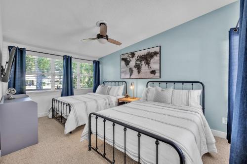 two beds in a bedroom with blue walls and windows at Best of Both Worlds Lakehouse in Orlando