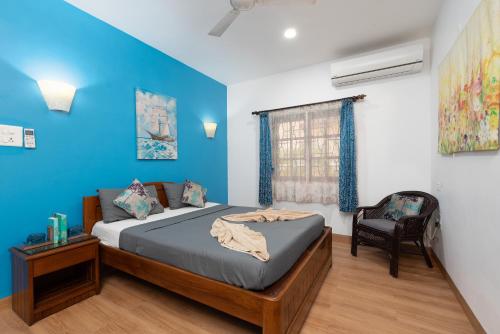 a bedroom with blue walls and a bed and a chair at Villa Calangute Phase 3 in Calangute