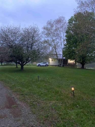 a car parked in a yard with trees and a house at Farm House in Coldwater