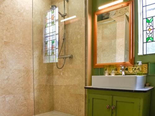 ein Bad mit einer Dusche, einem Waschbecken und einem Spiegel in der Unterkunft Owls Nest in Stradbroke