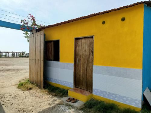 un pequeño edificio blanco y amarillo con puerta en Urantia Beach Hostel & Camping en San Onofre