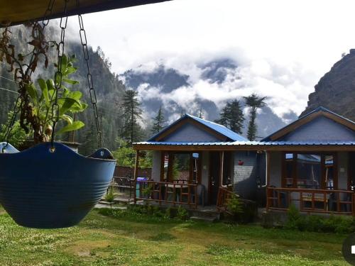 una casa con un gran columpio azul delante de ella en Lee Garden Himalayan Wooden Cottages, en Kasol