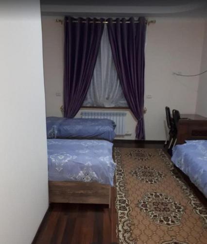 HOTEL ABU BAKIR في Denov: غرفة نوم بسريرين ونافذة ذات ستائر ارجوانية