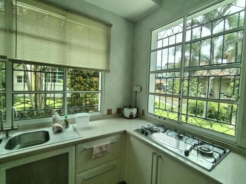 een keuken met twee ramen en een wastafel en een aanrecht bij KK Kiansom Retreat in Kota Kinabalu