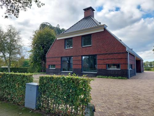 a large red brick house with a roof at Smaakvol Slochteren in Slochteren