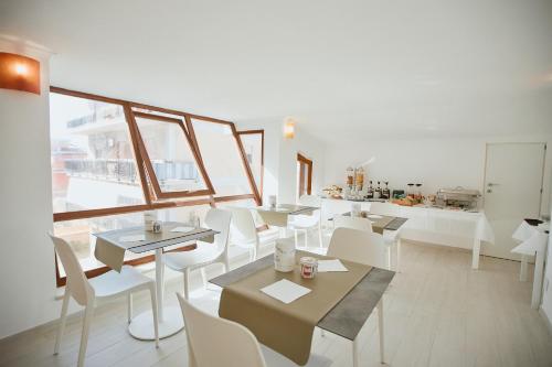 フィウミチーノにあるCastrichella Boutique Hotel Rome Airportの白いテーブルと白い椅子が備わるレストラン