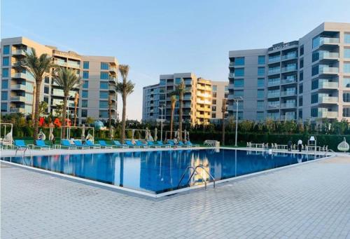 duży basen z palmami i budynkami w obiekcie Elegant and comfortably furnished 2BRH apartment in a quiet area! w Dubaju