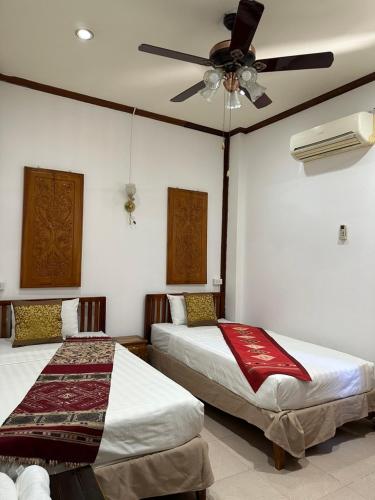 a bedroom with two beds and a ceiling fan at Mano boutique sun shine in Luang Prabang