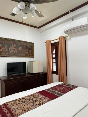 a bedroom with a bed and a flat screen tv at Mano boutique sun shine in Luang Prabang