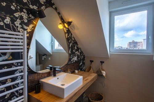 W łazience znajduje się umywalka i lustro. w obiekcie un Nid en Ville -Amiens Centre ville avec Parking w Amiens