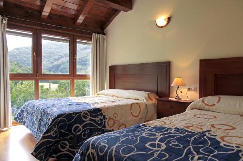 a bedroom with two beds and a large window at Apartamentos Irati Olaldea in Oroz-Betelu