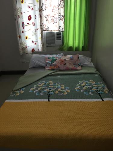 a bed with a blanket on it with a window at AGB Anchorage Inn, studio room in Manila