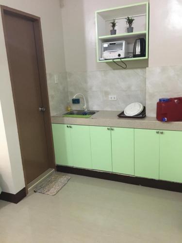a kitchen with green cabinets and a microwave at AGB Anchorage Inn, studio room in Manila