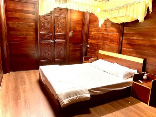 Schlafzimmer mit einem Bett und Holzwänden in der Unterkunft Biệt thự gỗ Mê Linh in Lam Ha