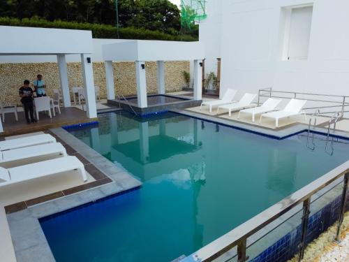 長灘島的住宿－L'eau Bleue Boracay Condotel，一个带白色椅子的游泳池,海水蓝色