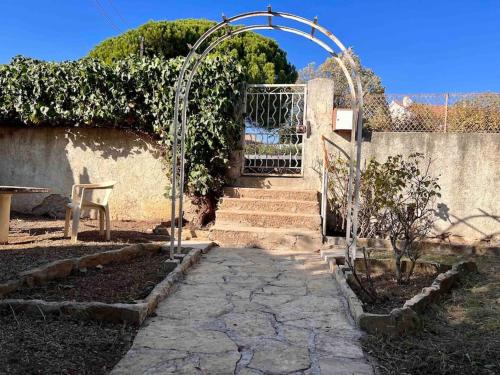 un jardin avec un portail et une passerelle en pierre dans l'établissement Charmant haut de villa T3, à Saint-Cyr-sur-Mer