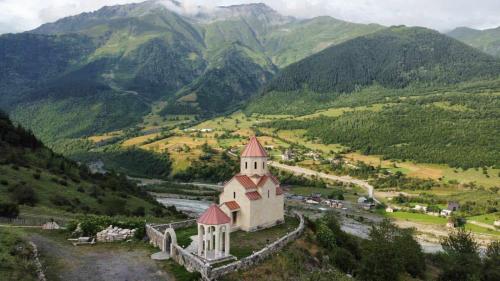 a small church on a hill with mountains in the background at Mishgu Qor in Mestia