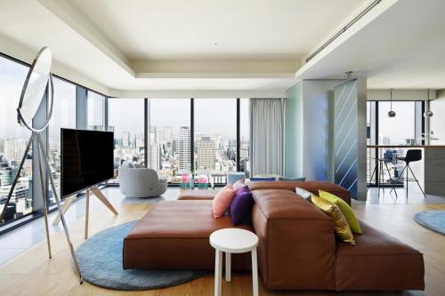 a living room with a couch and a large window at W Osaka in Osaka