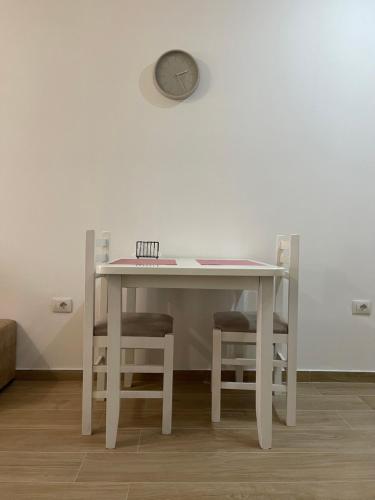 una mesa blanca con dos sillas y un reloj en la pared en Gex apartments en Tirana