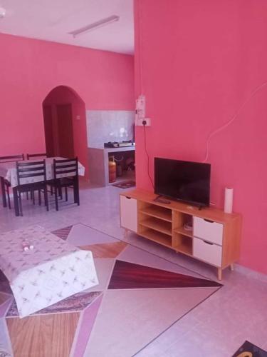 een woonkamer met een rode muur en een flatscreen-tv bij Homestay kak nun in Kampong Ru Sepuloh