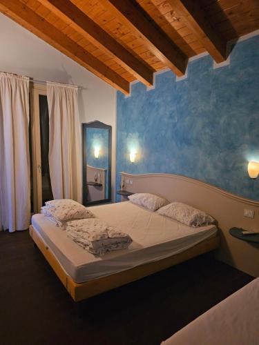 1 dormitorio con 1 cama con pared azul en Via Fantoni 4, en Castione della Presolana