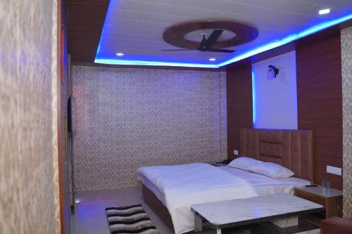 a bedroom with a bed and a ceiling with a blue light at JB Hotel and Resort in Lohaghāt