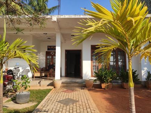 une maison avec des palmiers devant elle dans l'établissement Sunhill Lake Tourist Rest, à Anurâdhapura